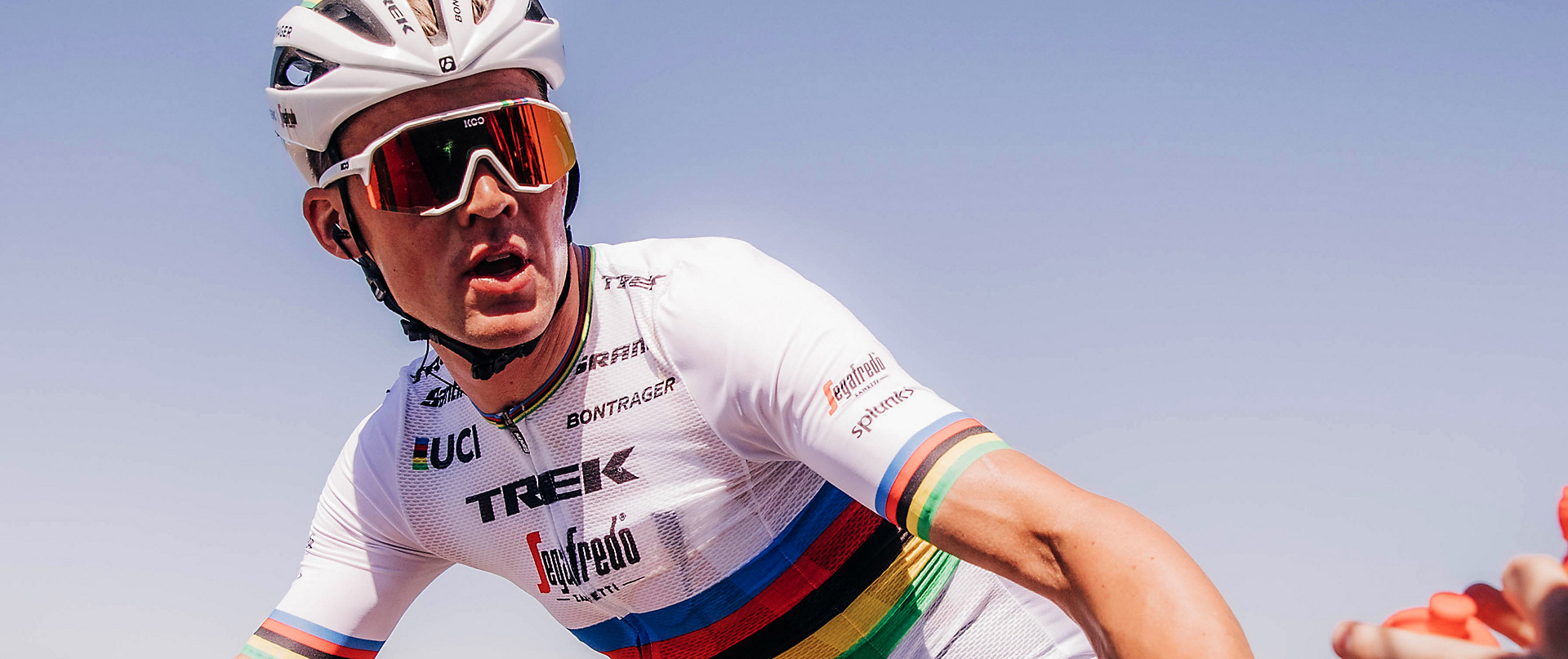 Mads Pedersen in his rainbow jersey, sunglasses, and a helmet.